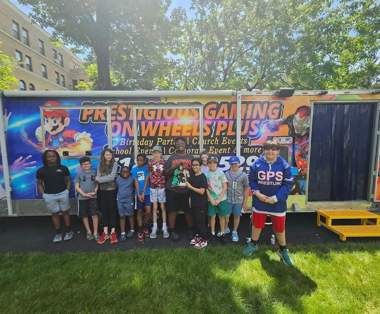 Group of kids posing in front of the game truck at a birthday party