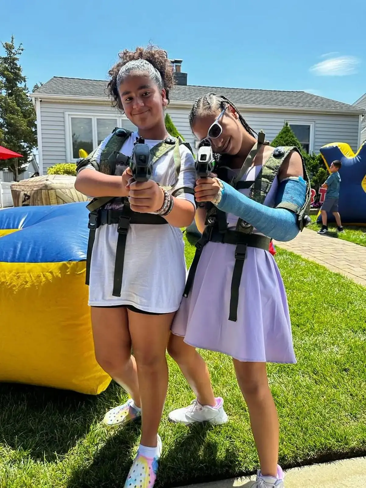 Two friends holding laser tag blasters at a backyard party