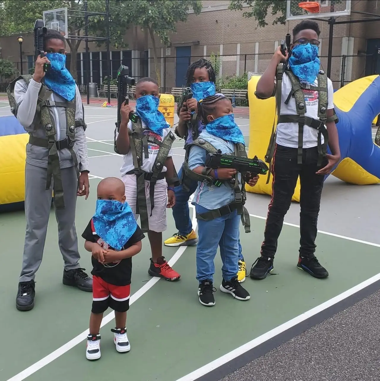 Laser tag team in vests posing with blasters on a basketball court