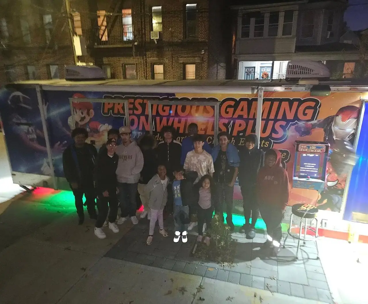 Party guests gathered outside the illuminated game trailer at night
