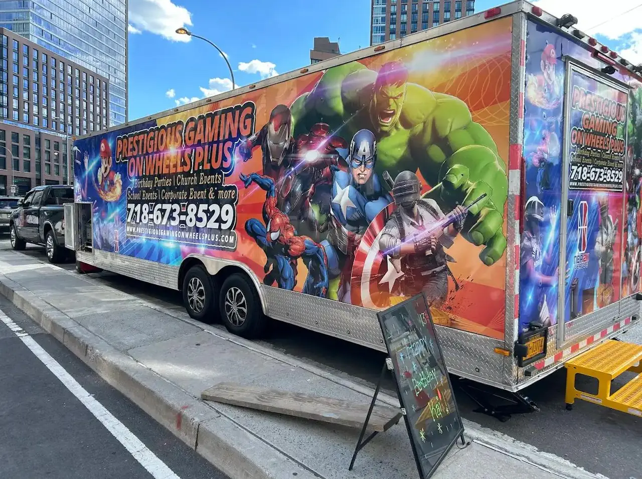 Superhero-wrapped video game trailer parked on a city street